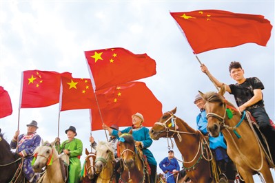 内蒙古自治区鄂尔多斯市鄂托克旗牧民在赛马活动中高举国旗,共祝伟大