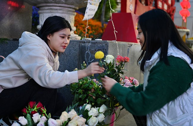 3月27日，镇坪县城关镇的史棻棻（左）在夜市销售鲜花。新华社记者 陶明 摄